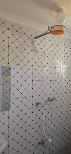 a shower in a bathroom with a white tiled wall at Cedar Suites in Juja
