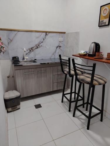 a kitchen with two chairs and a counter with a sink at Alojamiento Ruta 51 in La Banda