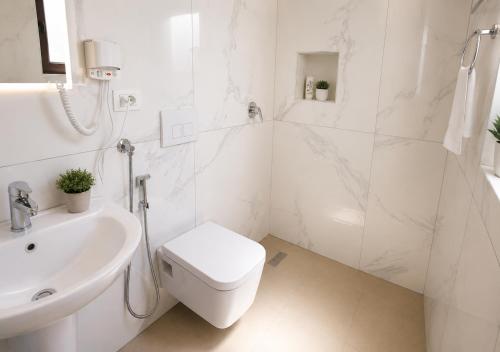 a white bathroom with a toilet and a sink at Villa Arli&Eris in Vlorë