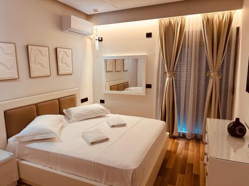 a bedroom with a white bed and a mirror at Vasili Apartament in Gjirokastër