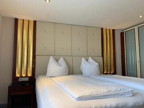 a bedroom with a bed with white sheets and pillows at Berggasthof Immenstein in Bühl