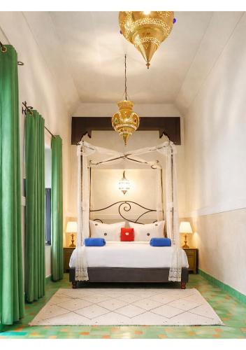 a bedroom with a canopy bed with green curtains at Riad ABBASSIA Marrakech Première - Authentic Medina Experience in Marrakesh