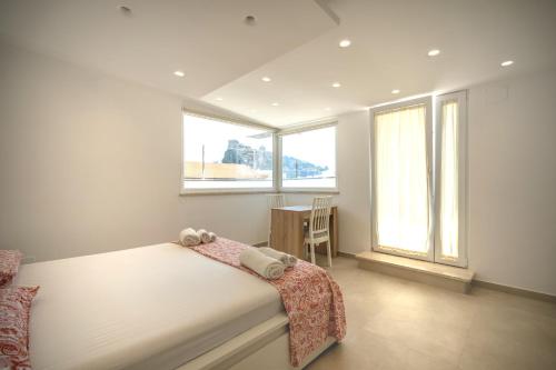 a bedroom with a bed with a desk and windows at Aragonese Apartments in Casa Chiaiozza