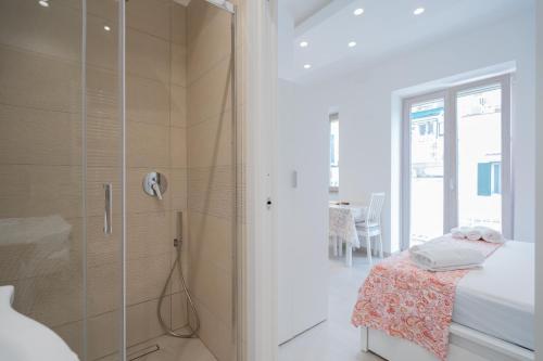 a white bathroom with a shower and a bed at Aragonese Apartments in Casa Chiaiozza