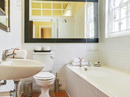 a bathroom with a sink and a toilet and a tub at Liberty Lodge Guest House in Cape Town