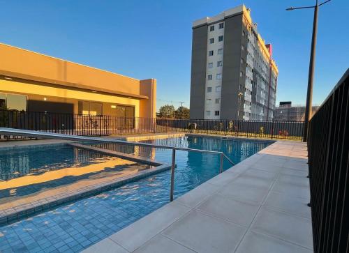 a swimming pool in front of a building at Apartamento próximo ao Aeroporto e Curitiba in São José dos Pinhais
