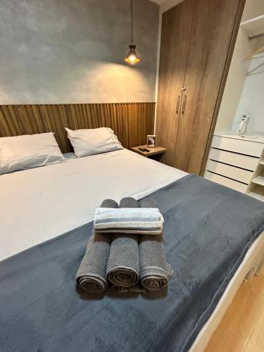 a bedroom with a bed with towels on it at Flat Completo no Centro de Itaboraí Promenade Prime in Itaboraí