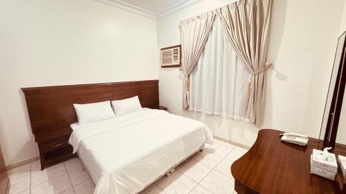 a bedroom with a bed and a table with a telephone at شقق أماسي الواحة بالعقيق in Al ‘Aqīq