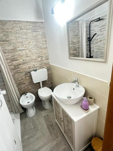 a bathroom with a sink and a toilet and a mirror at La tenuta di Greta in Canino