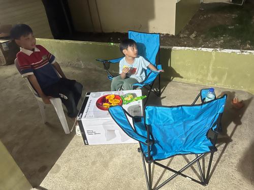 two boys sitting in chairs next to a table at Alexeis Place in Manolo Fortich