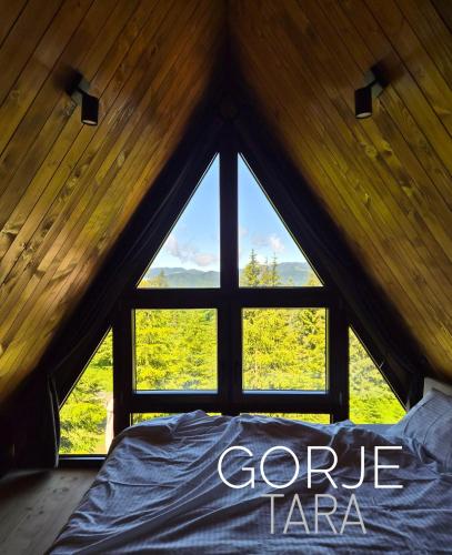 a bed in a room with a large window at Vrleti Tare in Bajina Bašta