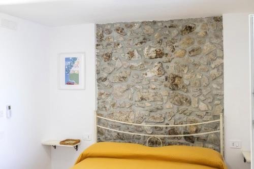 a bedroom with a stone wall behind a bed at Annalì in Trentinara