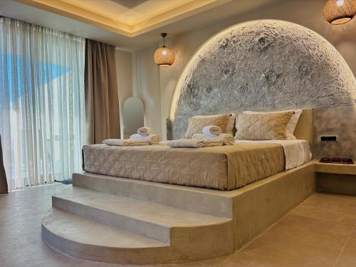a bedroom with a large bed with a stone headboard at Bevimar Suites with Private Pool and Non Heated Jacuzzi in Santorini