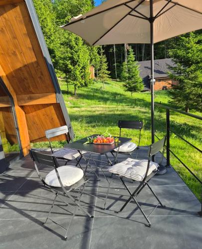 a patio with a table and chairs and an umbrella at Vrleti Tare in Bajina Bašta