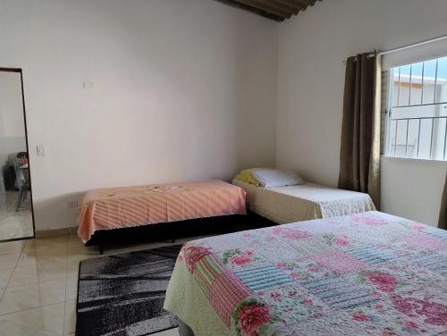 a room with three beds and a window at Microcasa espaçosa e acolhedora in Caraguatatuba