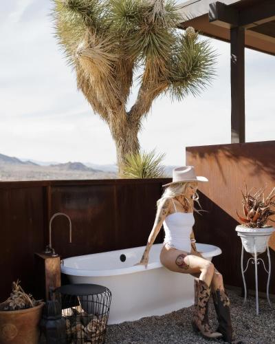 a woman in a white dress and hat sitting next to a bath tub at Sacred Sands - Lobo Luna in Joshua Tree