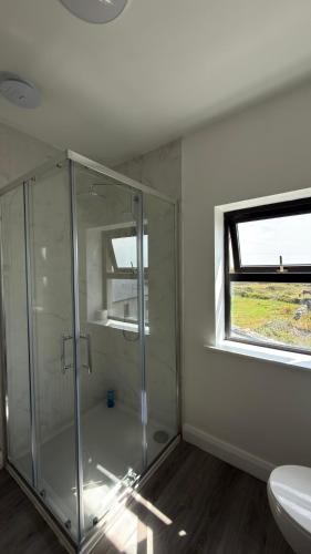 a bathroom with a shower and a toilet and a window at Dwellinghouse, Inishmore in Ourtnagapple