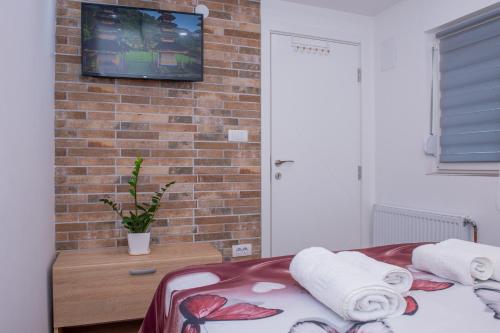 a bedroom with a tv on a brick wall at Apartman Živković in Leskovac