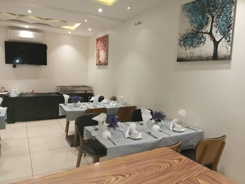 a dining room with tables and chairs and a tv at Hotel Occazia Lubumbashi in Lubumbashi