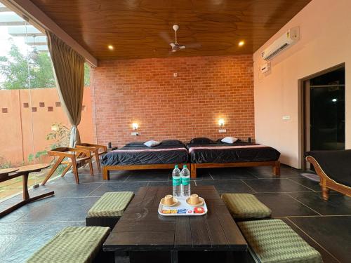 a room with two beds and a table and benches at Villa Saffron Luxury Pvt Pool in Pondicherry