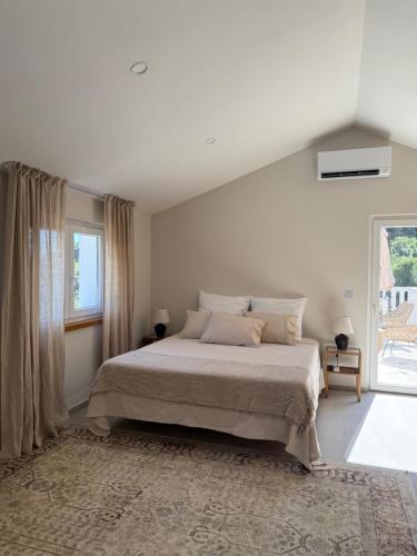 a white bedroom with a bed and a large window at Villa Ljeto in Pupnatska Luka
