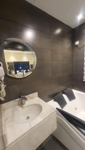 a bathroom with a sink and a tub and a mirror at sala almasa serviced apartments in Abha