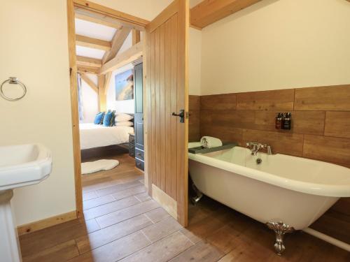 a bathroom with a bath tub and a bedroom at Lady Bagots Cabin in Ruthin