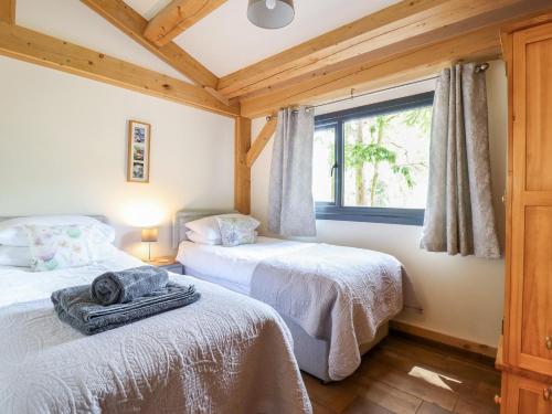 two beds in a room with a window at Lady Bagots Cabin in Ruthin