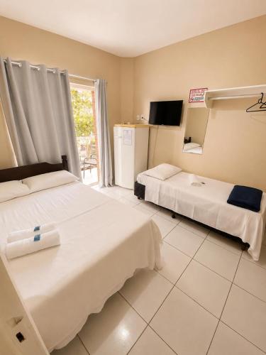 a hotel room with two beds and a television at Caminho do Mar Hotel in Guarujá