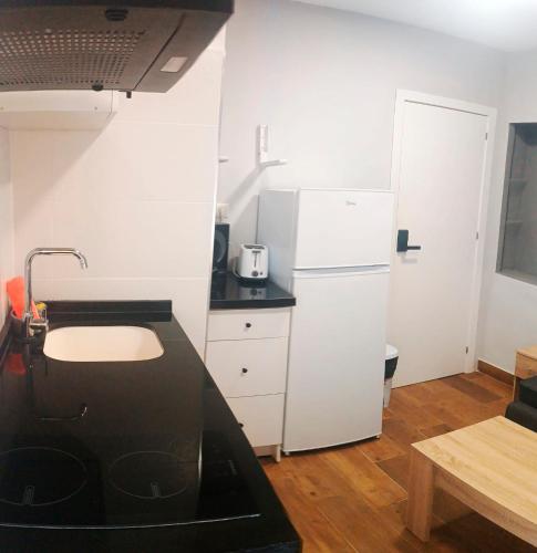 a kitchen with a black counter and a white refrigerator at Apartamento El Centro in Algarrobo