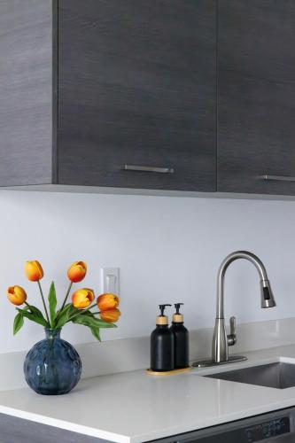 a kitchen counter with a vase with orange flowers in it at Chic Studio by Brickell & Miami Beach WD Pool Gym in Miami