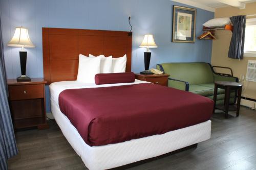 a hotel room with a large bed and a chair at Claremont Motor Lodge in Claremont