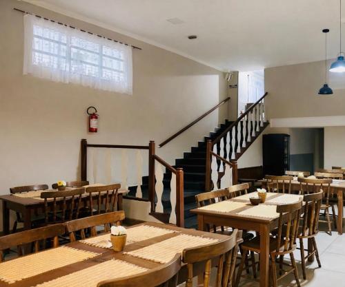 a restaurant with wooden tables and chairs and a staircase at Caminho do Mar Hotel in Guarujá