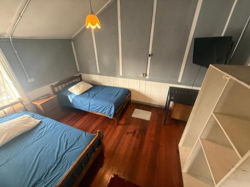 a small room with two beds and a television at Hostal Papo in Osorno