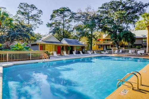 a swimming pool with chairs and a house at Beachwalk 124 in Hilton Head Island