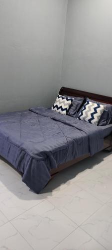 a bed with a blue comforter and pillows at HomeStay Rafiza in Jertih
