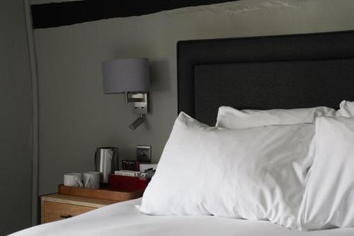 a bed with white pillows and a black headboard at The Windmill in Maidstone