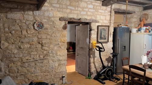a room with a stone wall with a door and a refrigerator at Le soleil se lève in Virac
