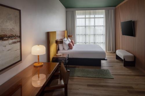 a hotel room with a bed and a table and a desk at The Clara Hotel Plano, Tapestry Collection by Hilton in Plano