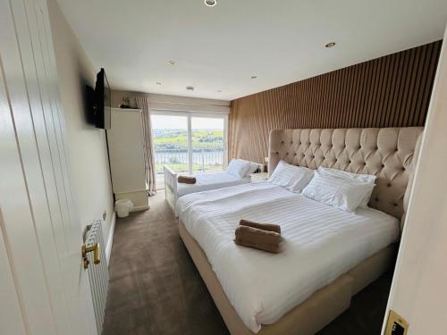 a bedroom with a large white bed with a large window at The Waterfront House in Kinsale, hosted by Exquisite Holiday Homes in Dunderrow