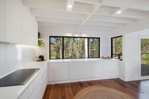 a kitchen with white cabinets and a large window at Maisie's in Tathra