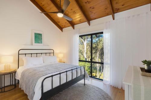 a bedroom with a bed and a large window at Maisie's in Tathra