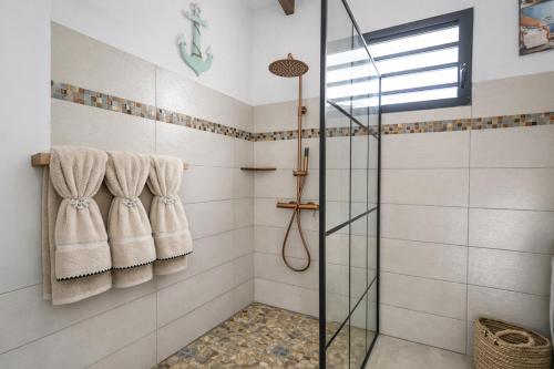 a bathroom with a glass shower stall and towels at L Échappée Belle Havre de paix au cœur du verger in Le Moule
