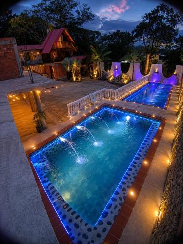 a swimming pool with lights in a backyard at night at Hotel La Parrilla Boyacense Rivera in Rivera