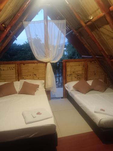 two beds in a room with a window at Hotel La Parrilla Boyacense Rivera in Rivera