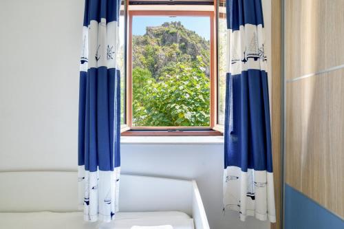 a window with blue and white curtains in a bathroom at Fiumera Kotor Apartment in Kotor