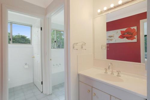 a bathroom with a sink and a tub and a mirror at Holiday on Pacific in Tathra