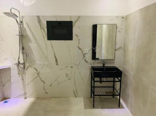 a bathroom with a marble wall with a sink and a mirror at Amazone in Ngaparou