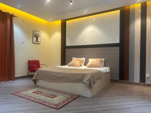 a bedroom with a large bed and a red chair at Residence MBK Appartement A in Ziguinchor