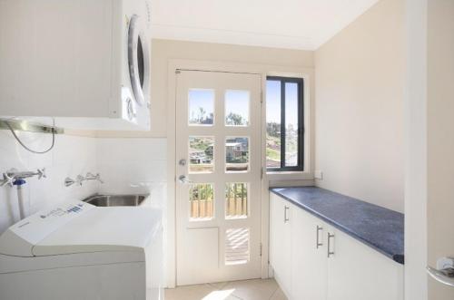 a white kitchen with a sink and a window at Fanta Sea in Tathra